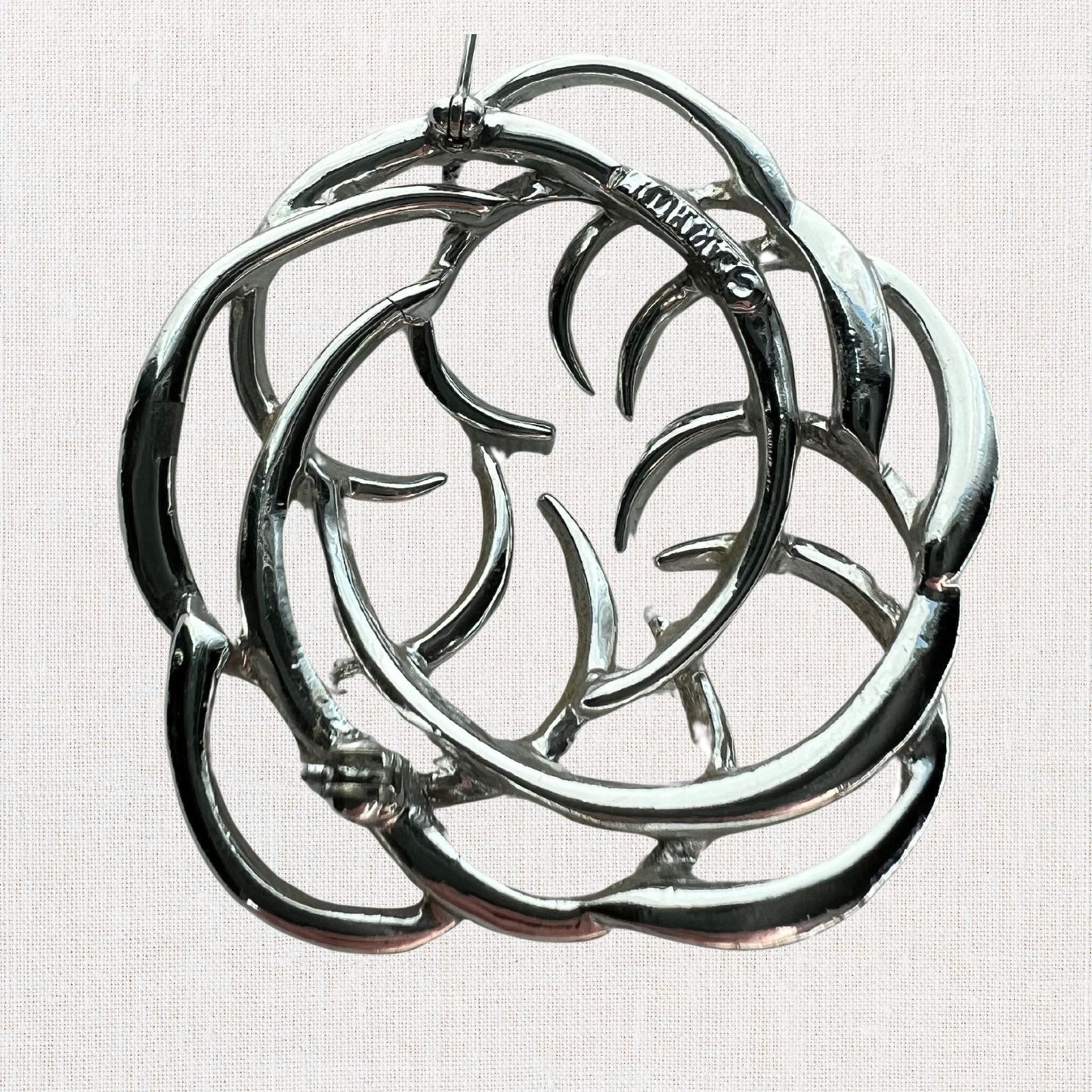 Silvertone interlocking circles brooch on neutral background, vintage home decor or collectible.