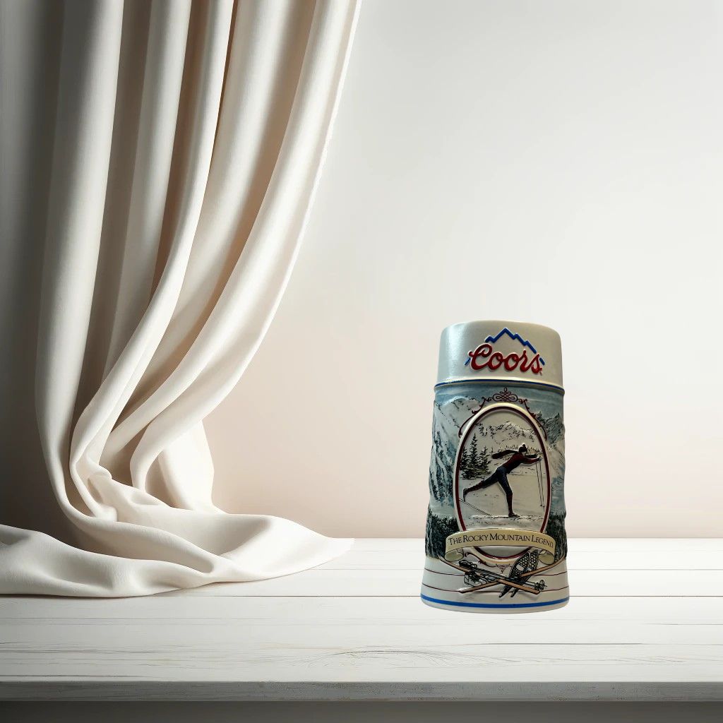 Coors 1990 ceramic beer stein with mountain motif, on neutral background, vintage home decor or collectible.