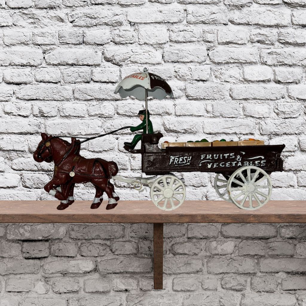 Cast iron horse drawn produce wagon on neutral background, vintage home decor or collectible.