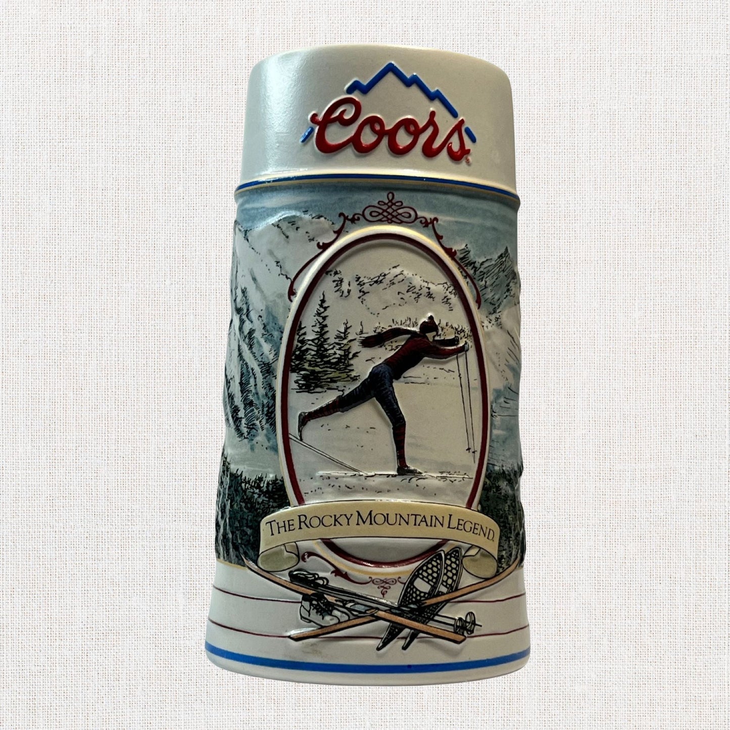 Coors 1990 ceramic beer stein with mountain motif, on neutral background, vintage home decor or collectible.