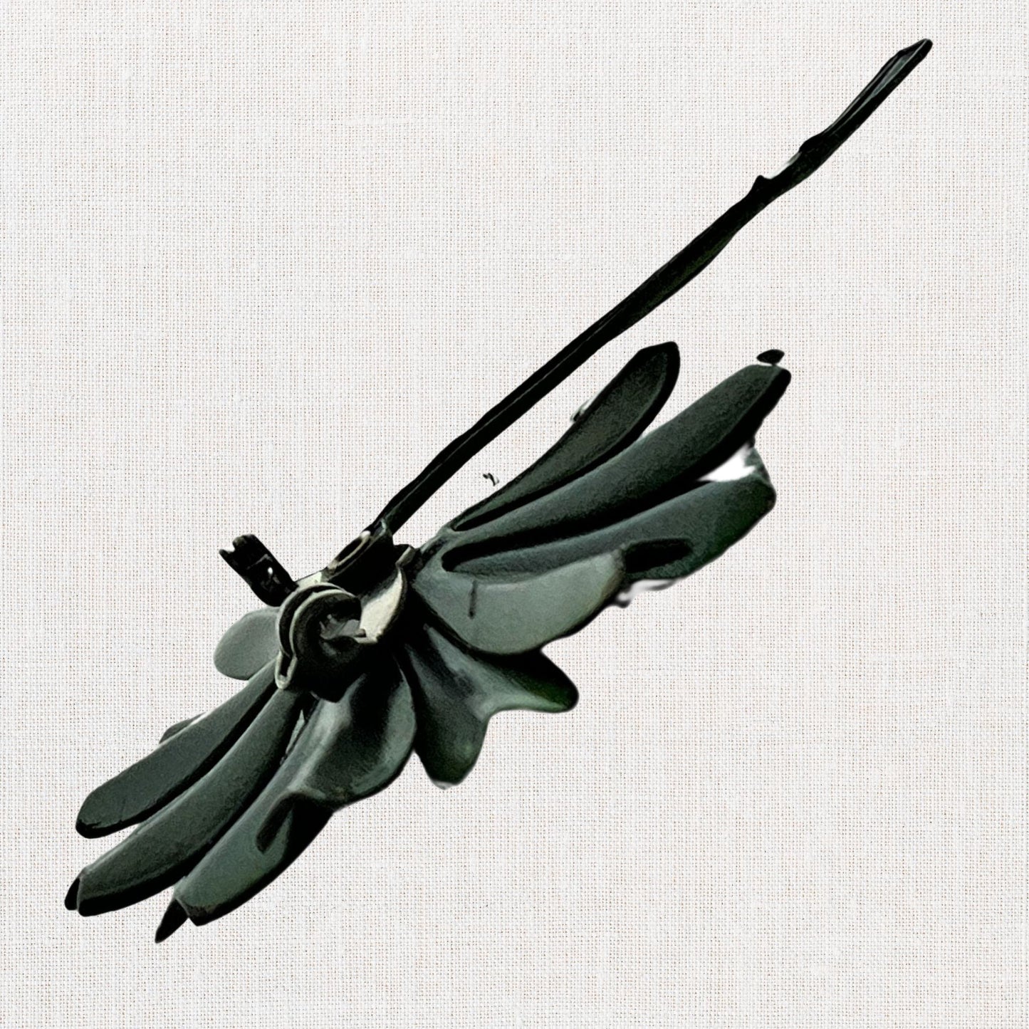 Green flower brooch with moveable stem on neutral background, vintage home decor or collectible.