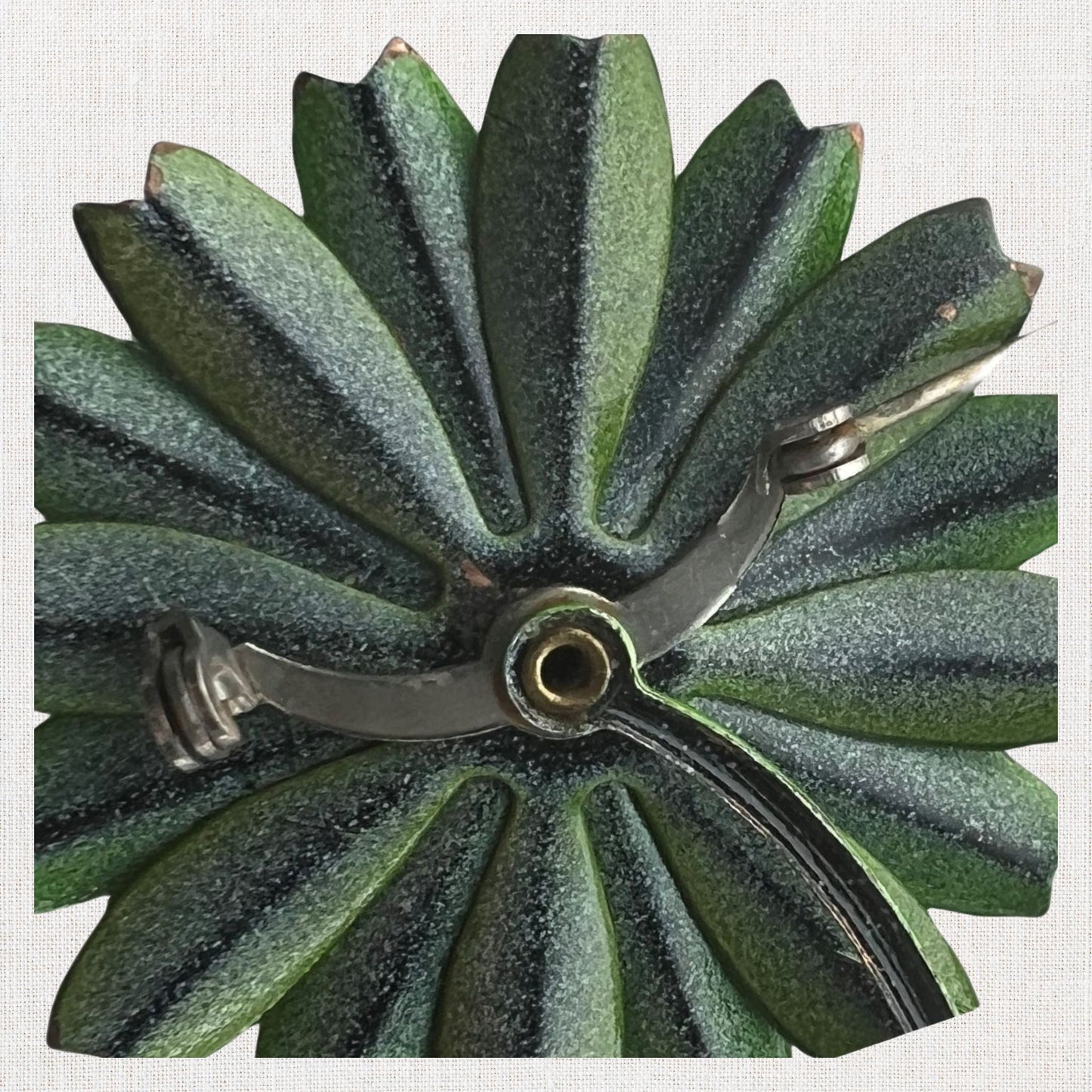 Green flower brooch with moveable stem on neutral background, vintage home decor or collectible.