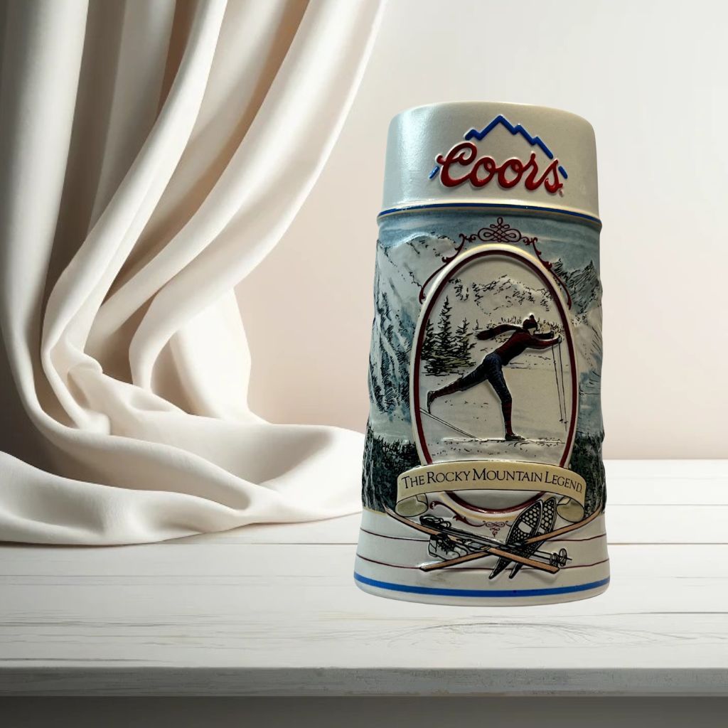 Coors 1990 ceramic beer stein with mountain motif, on neutral background, vintage home decor or collectible.
