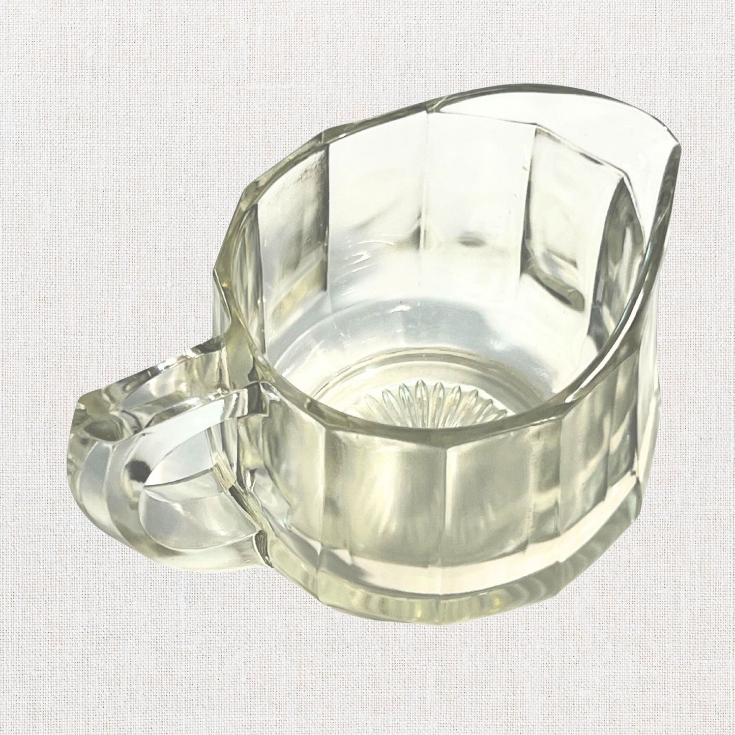 Clear glass ribbed creamer on neutral background, vintage home decor or collectible.