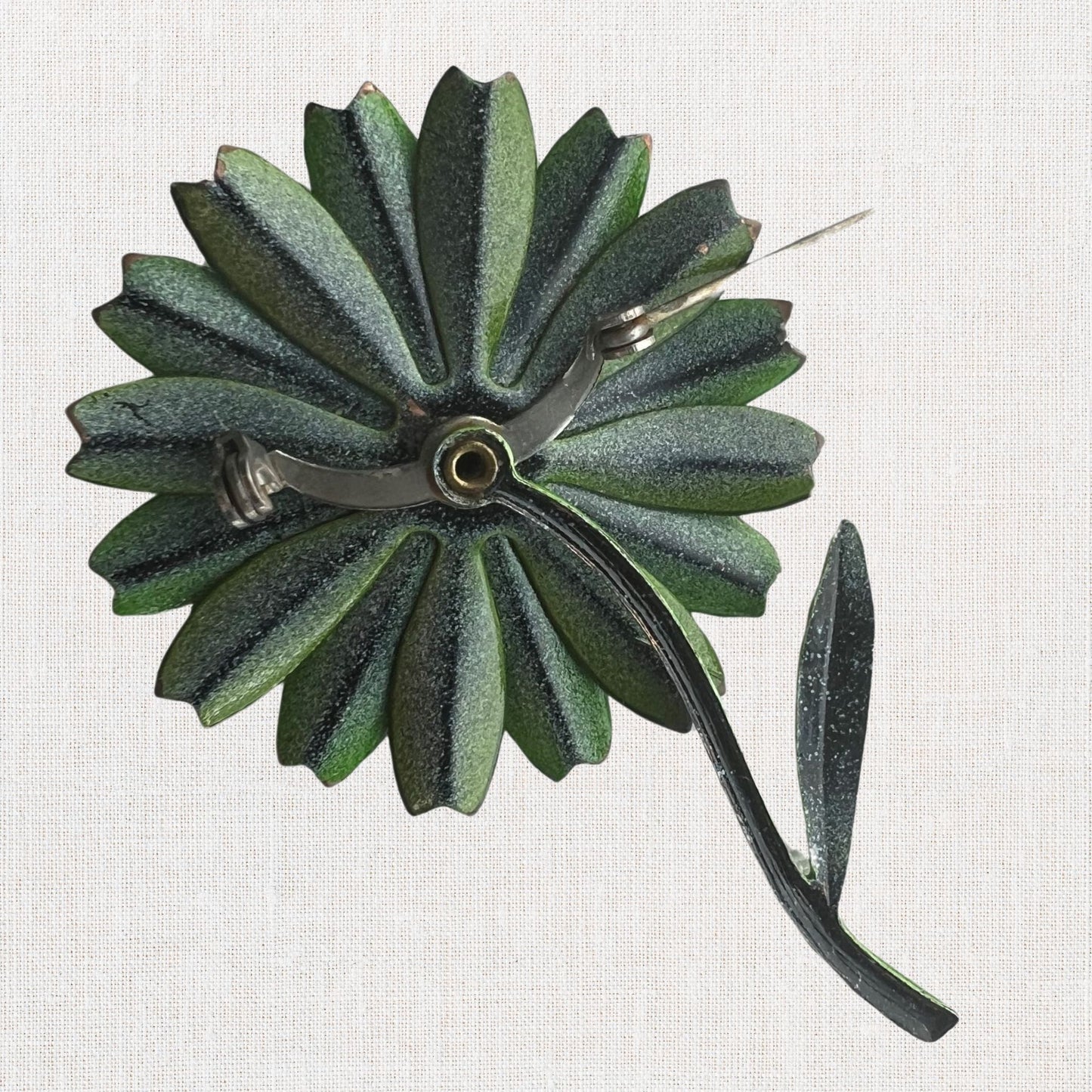 Green flower brooch with moveable stem on neutral background, vintage home decor or collectible.