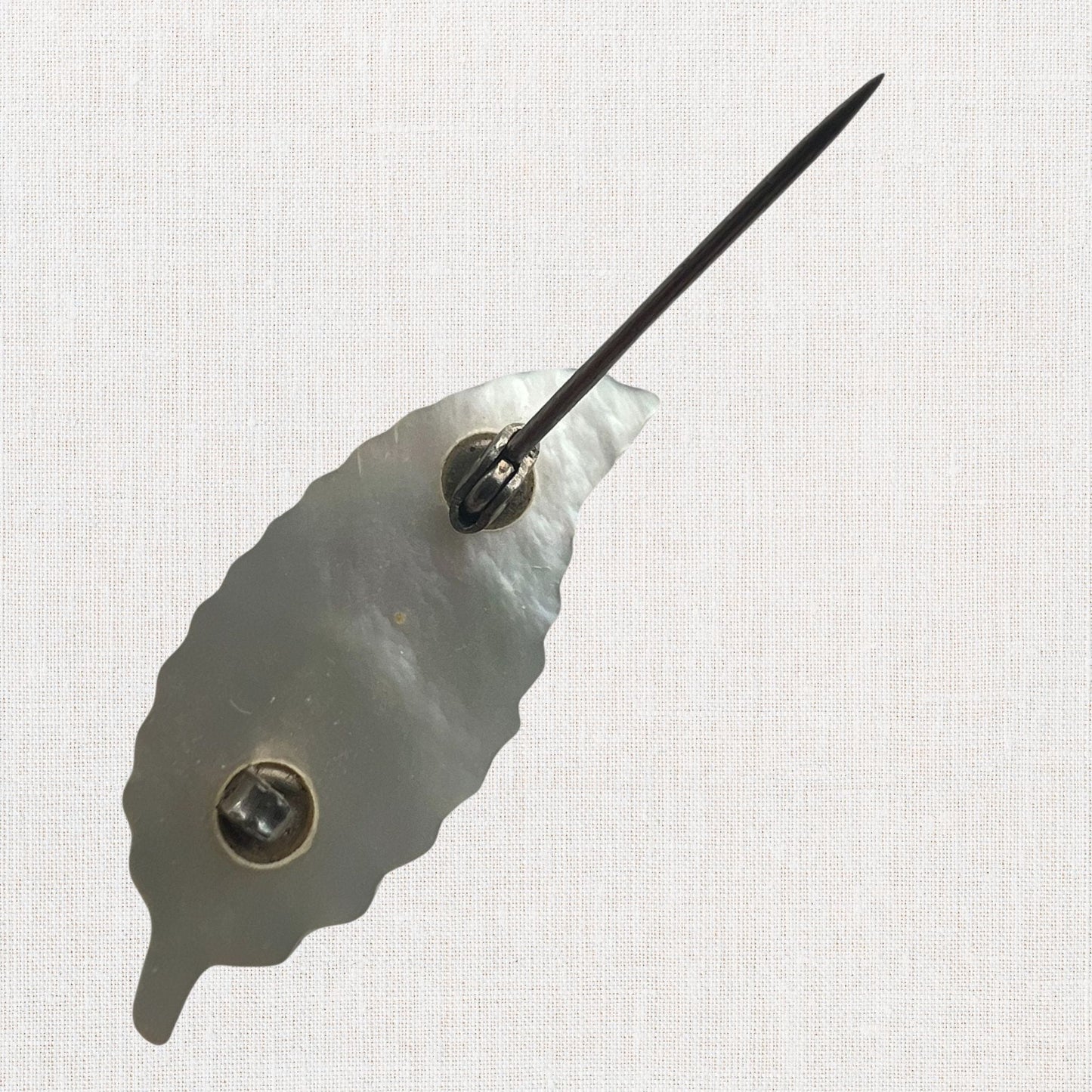 Mother of pearl miniature leaf brooch on neutral background, vintage home decor or collectible.
