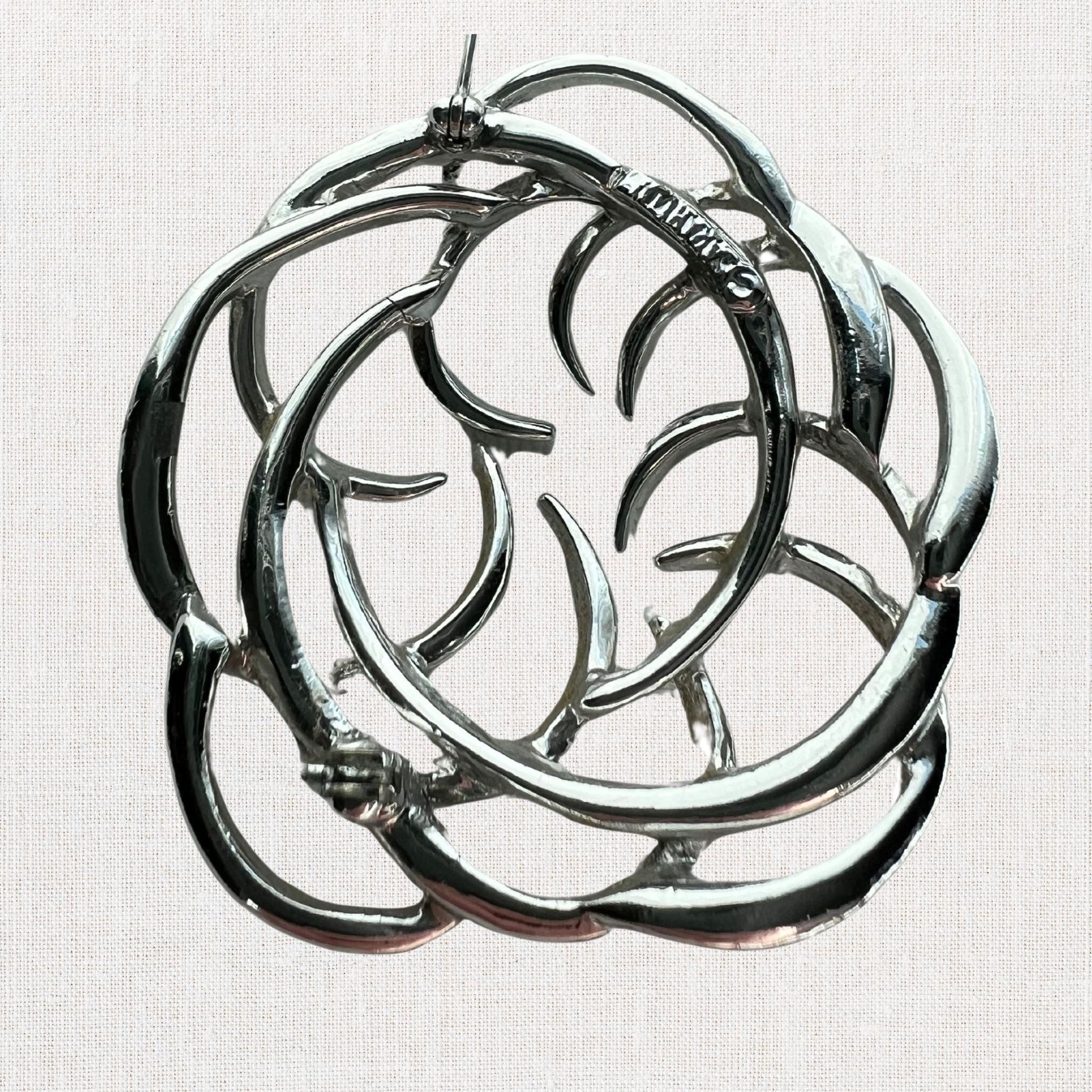Silvertone interlocking circles brooch on neutral background, vintage home decor or collectible.