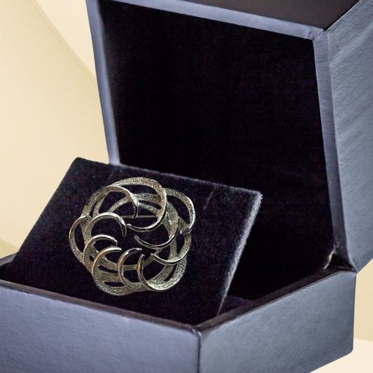Silvertone interlocking circles brooch on neutral background, vintage home decor or collectible.