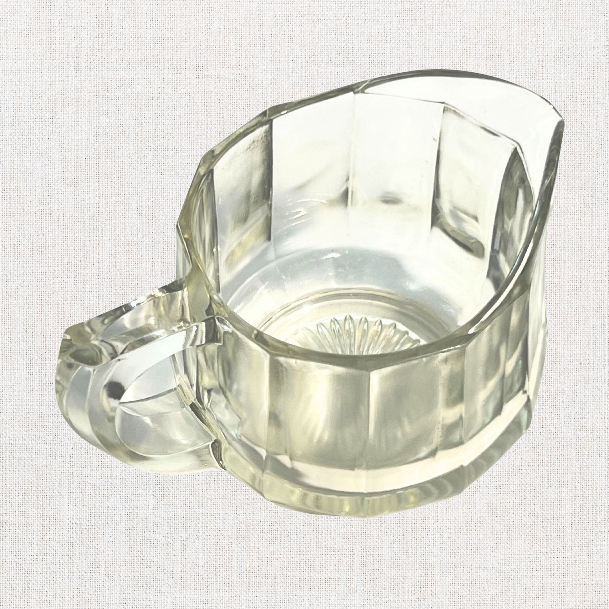 Clear glass ribbed creamer on neutral background, vintage home decor or collectible.