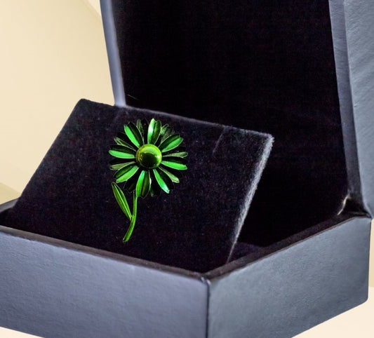 Green flower brooch with moveable stem on neutral background, vintage home decor or collectible.