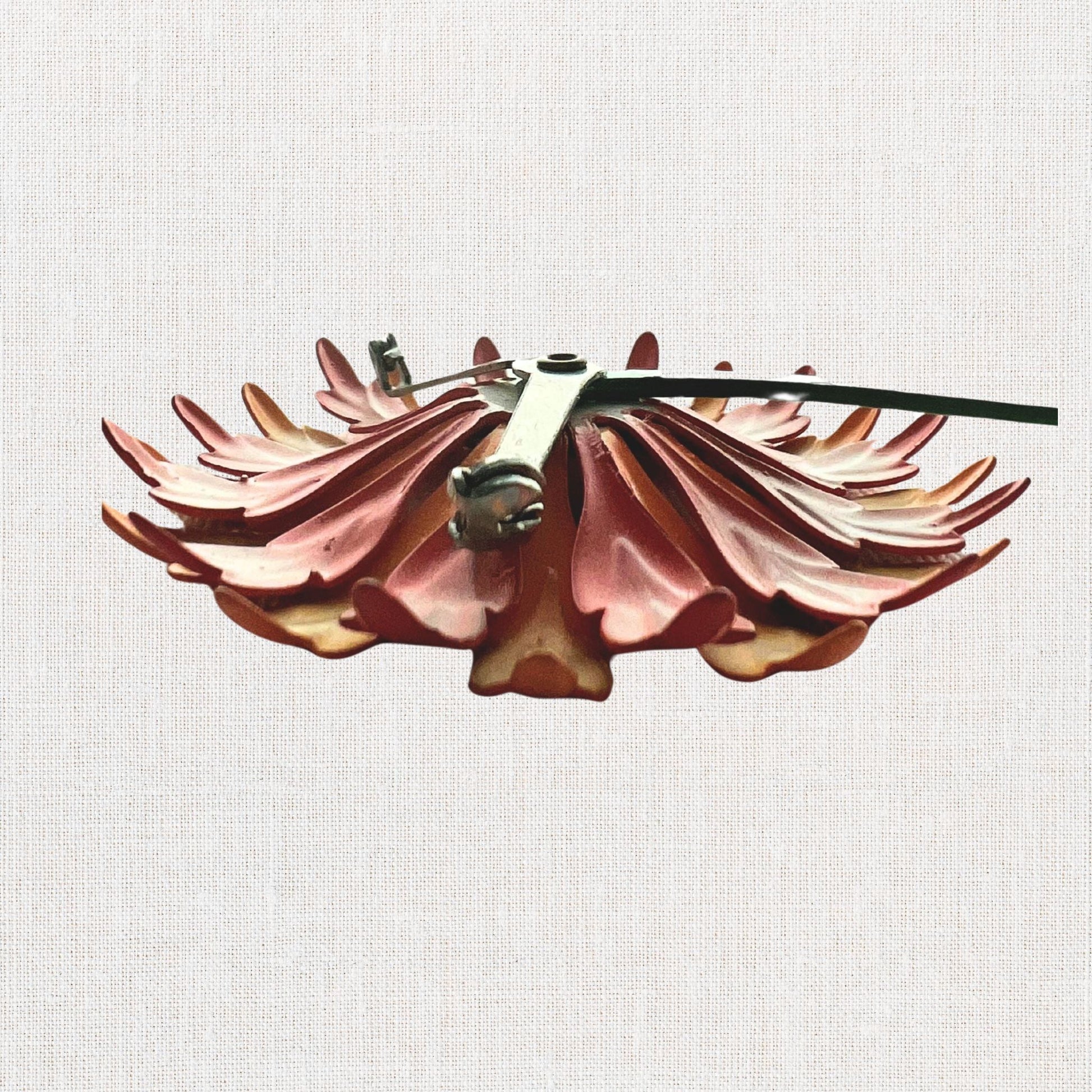 Pink flower brooch with moveable stem on neutral background, vintage home decor or collectible.
