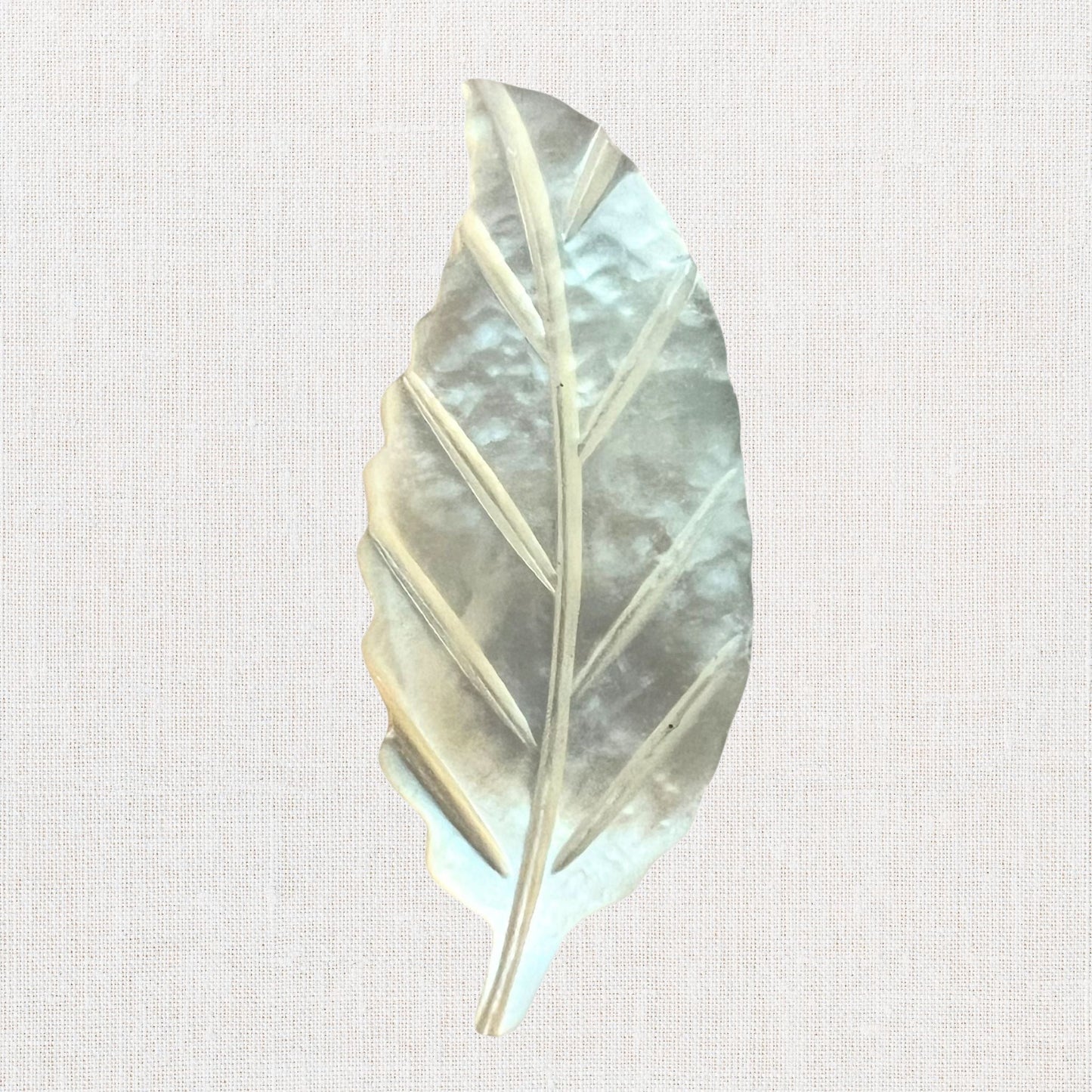 Mother of pearl miniature leaf brooch on neutral background, vintage home decor or collectible.