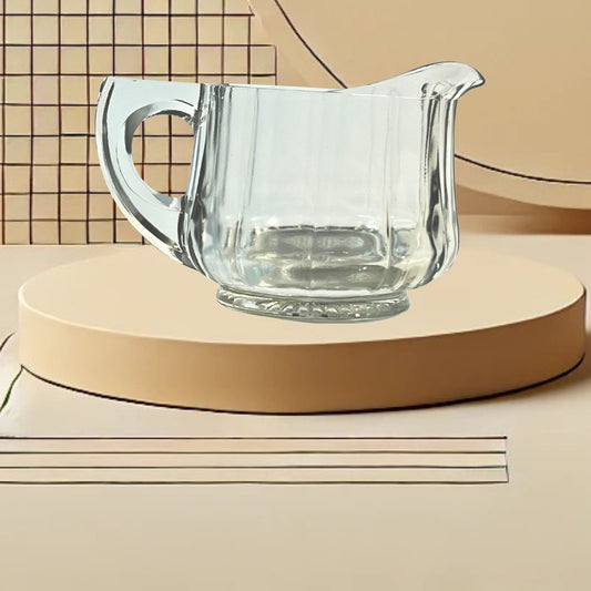 Clear glass ribbed creamer on neutral background, vintage home decor or collectible.